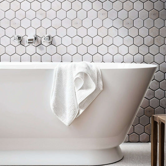 Elegant bathroom featuring a freestanding tub against a beige marble hexagon tile backdrop.