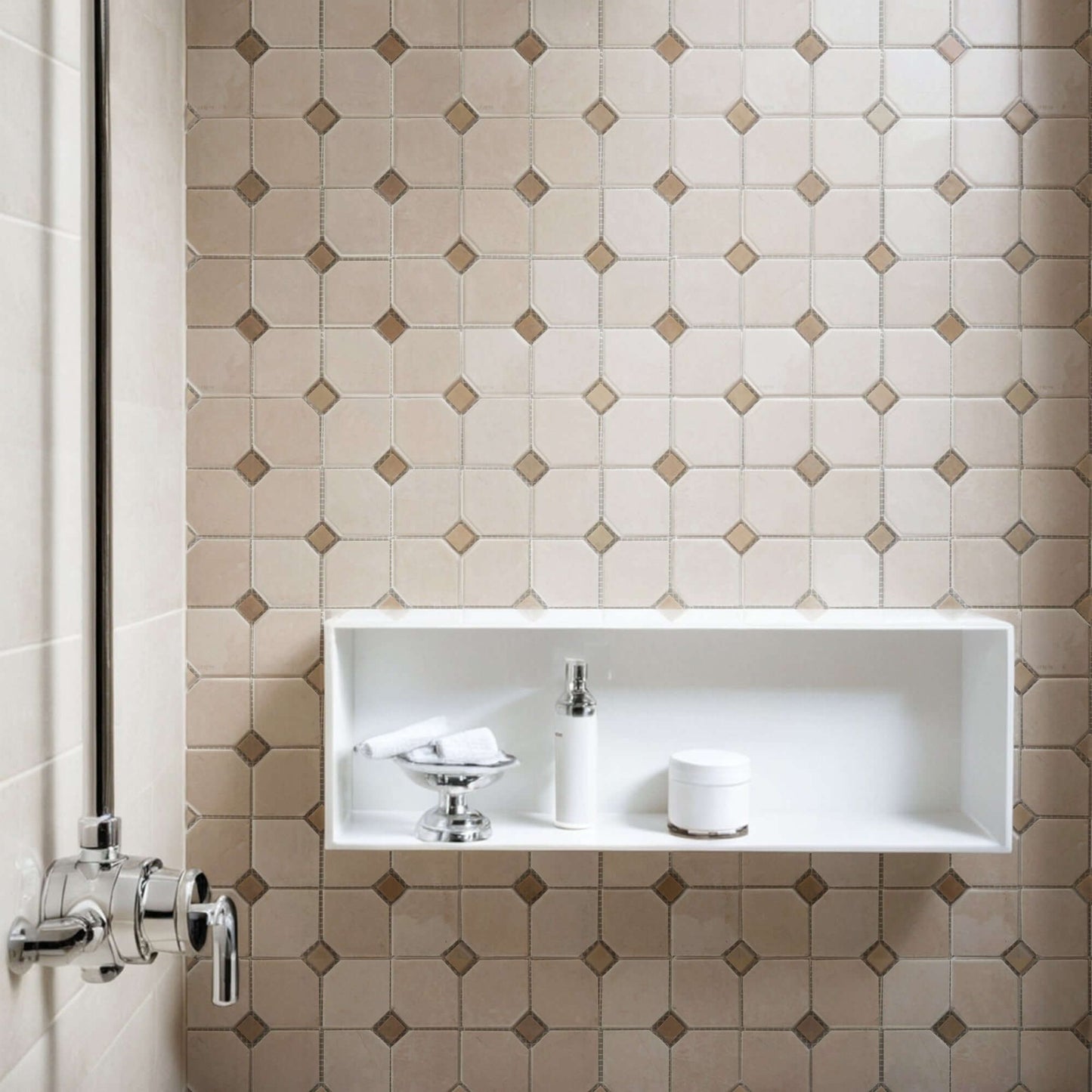 Beige marble mosaic tiles with a minimalist design in a modern shower setting featuring a white recessed shelf.