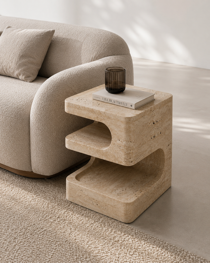 Cascade Travertine Side Table styled beside a sofa in a luxury modern living room.