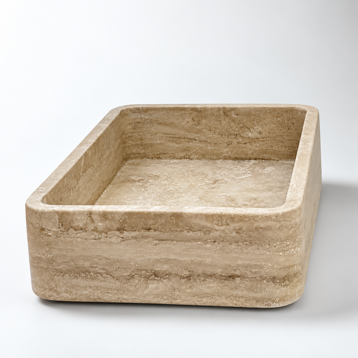 A rectangular stone basin with rounded corners and a textured beige travertine-like surface, shown on a clean white studio background.
