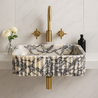 Calacatta Viola marble sink with gold faucet in modern bathroom setting, showcasing unique veining and elegant design.